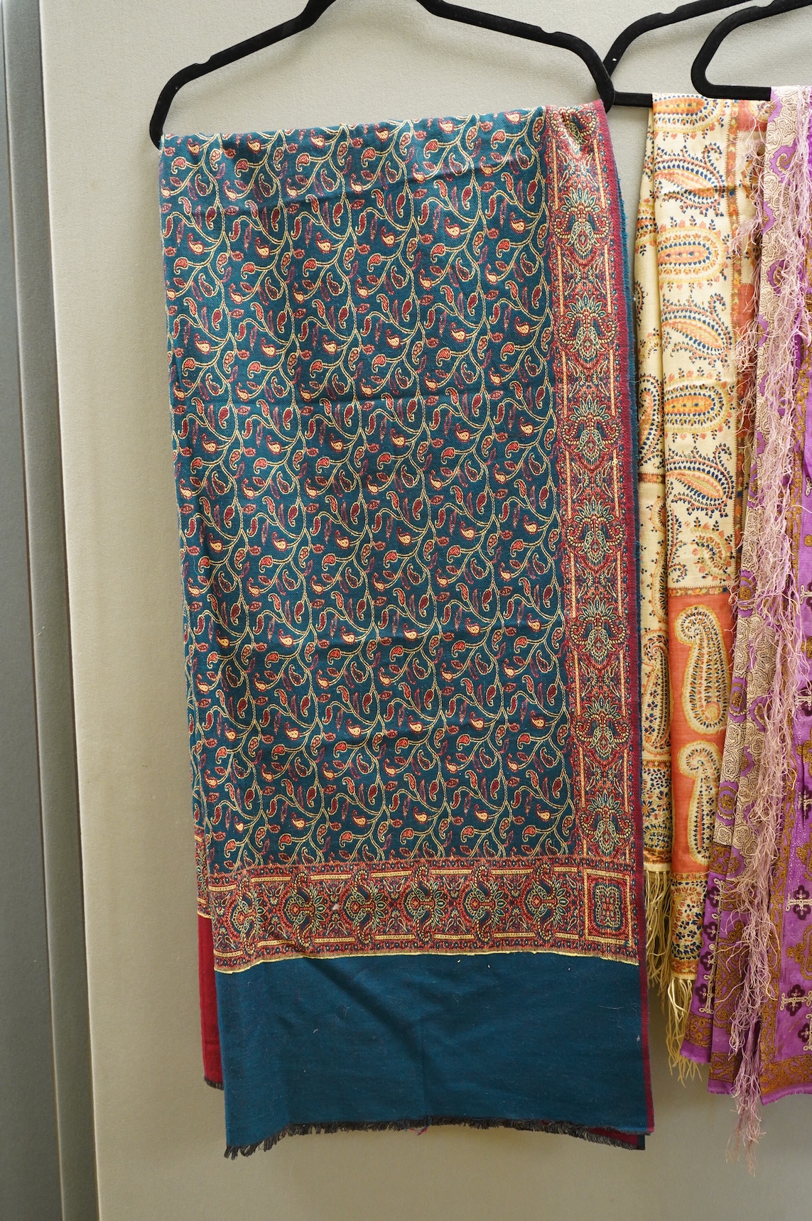 A 19th century printed silk shawl and a printed paisley shawl, together with a late 20th century wool machine woven stole with Oswal label. Condition - the two 19th century shawls are damaged but useful for TV and film c